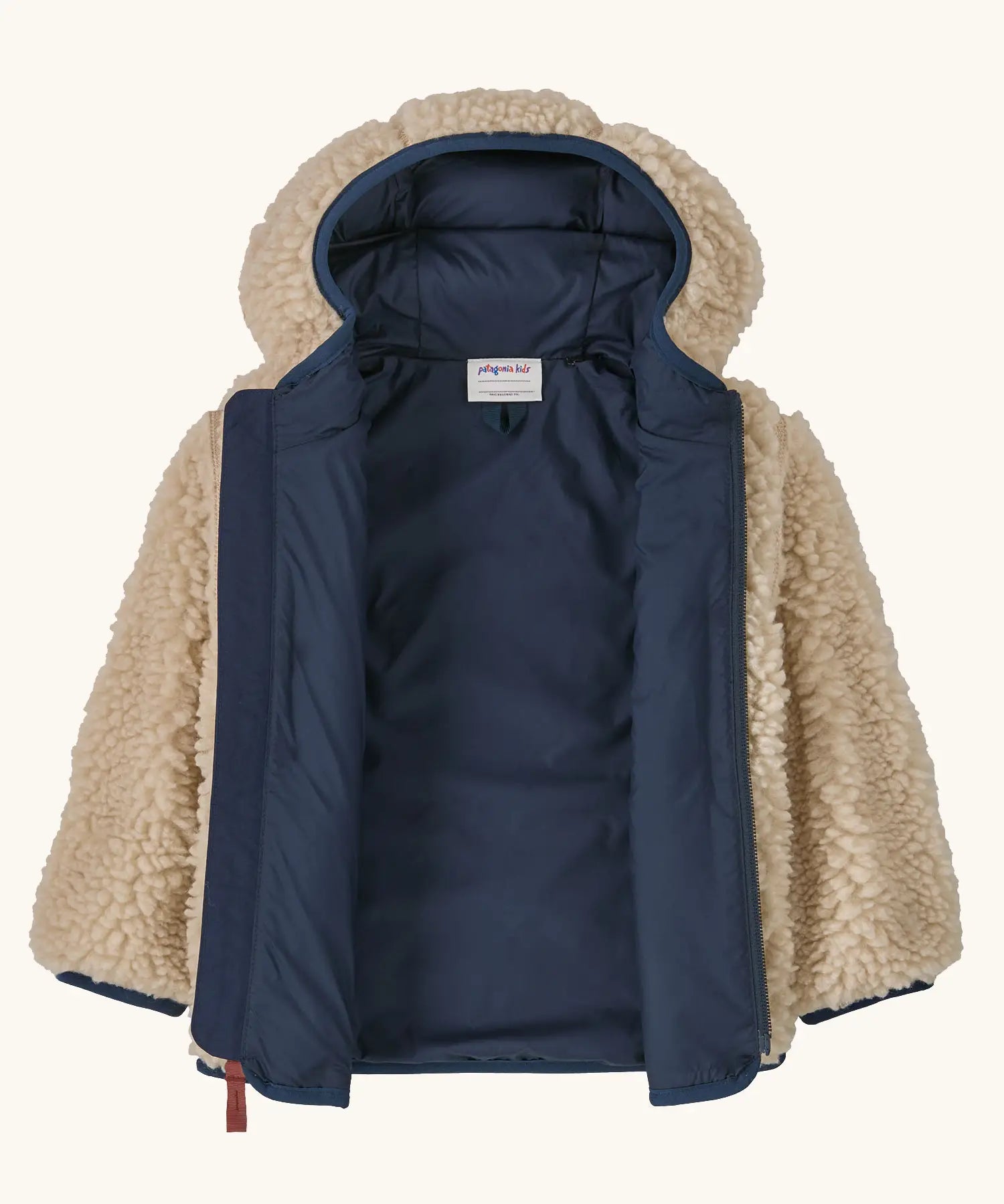 An open Patagonia little kids retro x pile windproof hooded fleece jacket in beige showing the navy inner liner