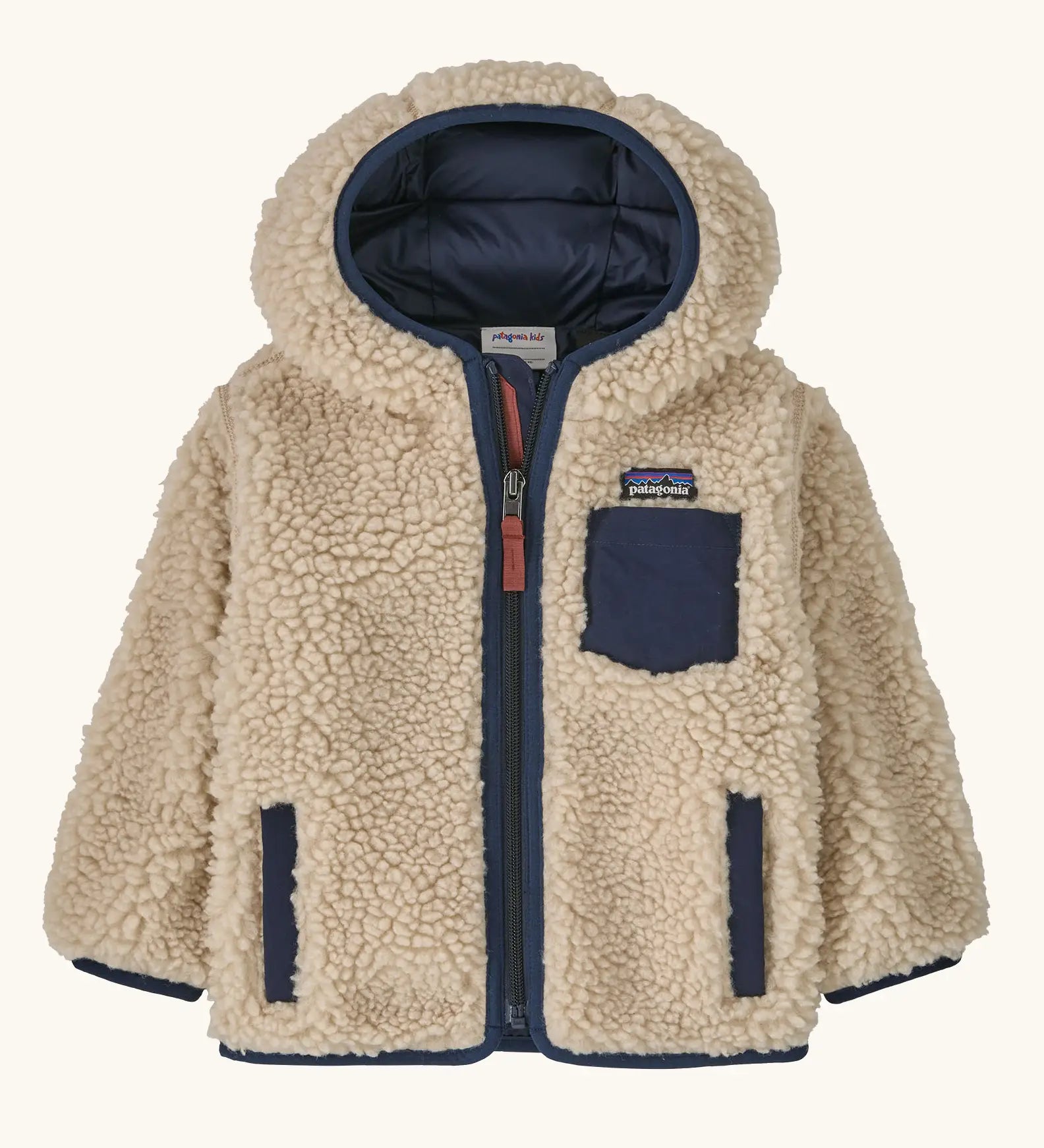 Patagonia little kids retro x pile windproof hooded fleece jacket in beige with a navy inner. Shows a full front zip, side and chest pockets