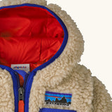 Patagonia little kids retro x pile fleece hooded jacket in beige showing a blue trim around the hood and top of the chest pocket