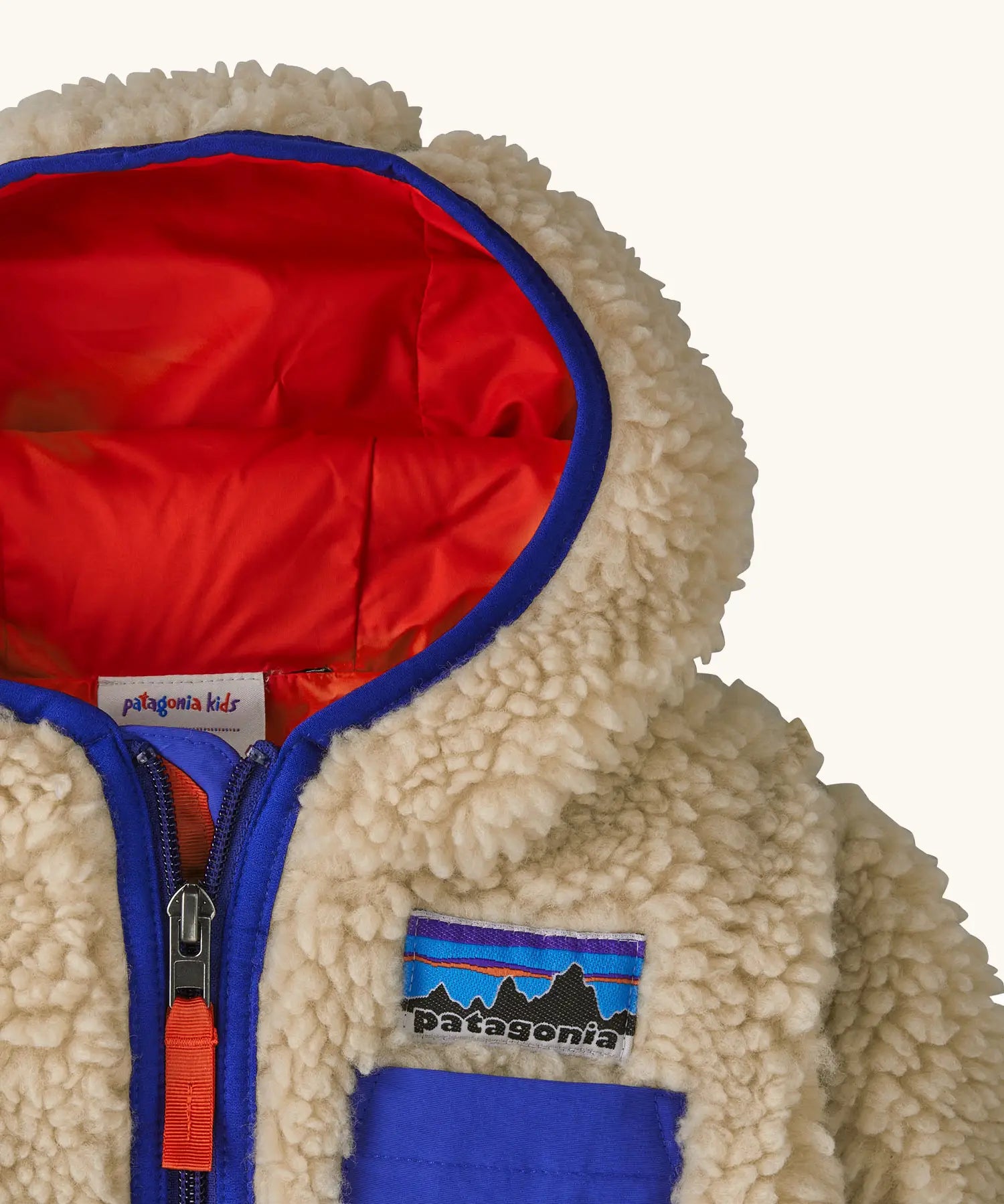 Patagonia little kids retro x pile fleece hooded jacket in beige showing a blue trim around the hood and top of the chest pocket