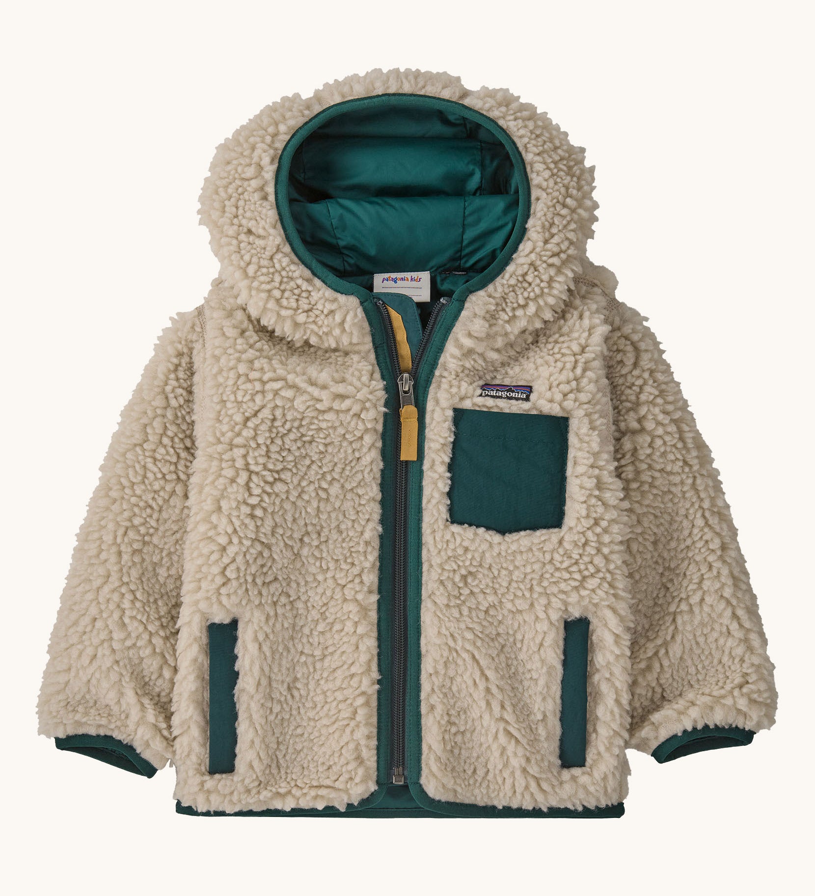 Patagonia little kids retro x hoody in dark natural /cascade green available at Babipur. A 100% recycled polyester thick pile fleece hooded jacket in cream with dark green trim Features a full length zip, 2 side pockets and a small chest pocket