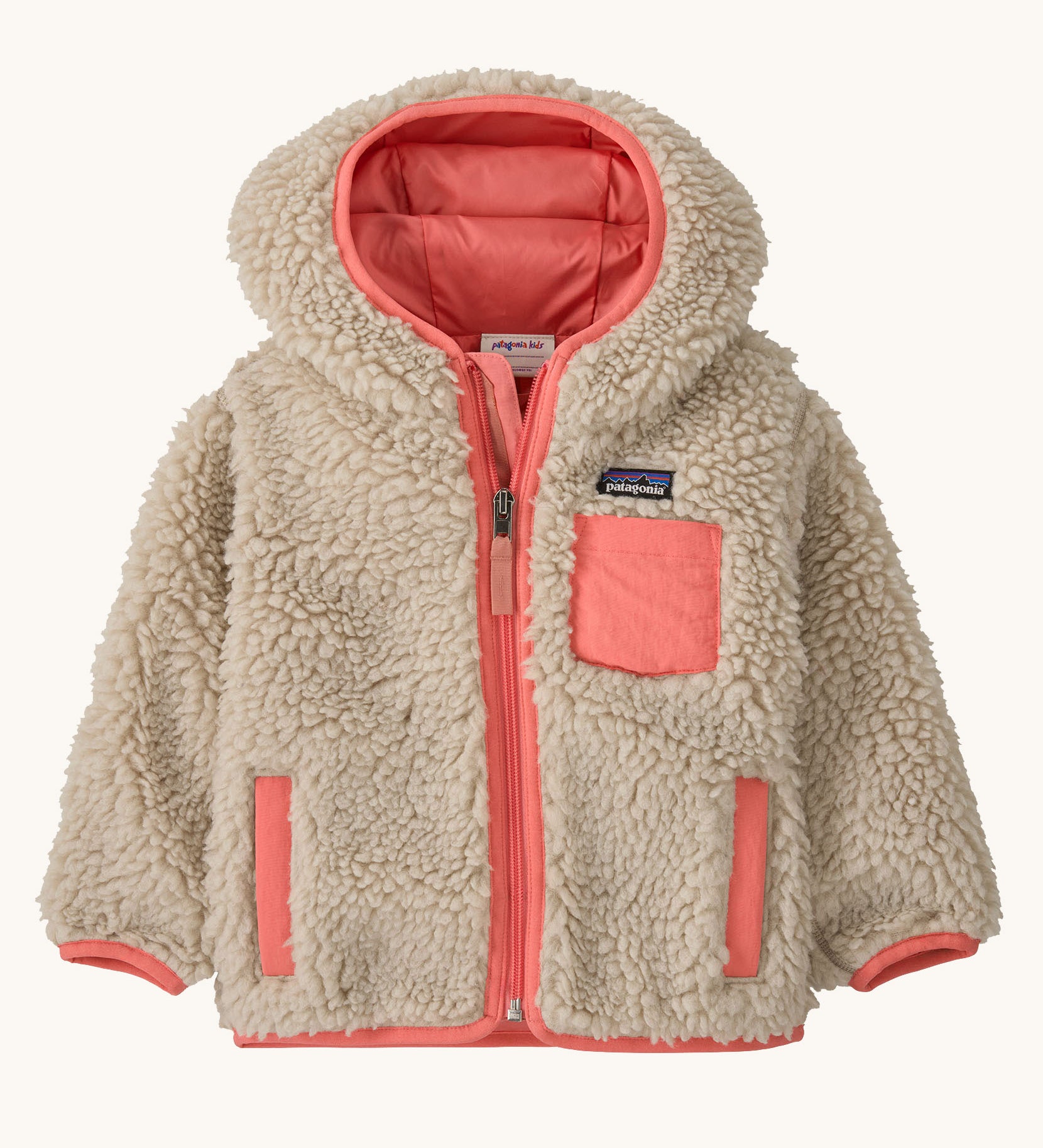 Patagonia little kids retro x hoody in dark natural available at Babipur. A 100% recycled polyester thick pile fleece hooded jacket in cream with pink trim Features a full length zip, 2 side pockets and a small chest pocket