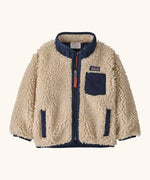 Patagonia little kids retro x pile fleece jacket in neutral with a navy trim. Shows a full front zip, side and chest pockets