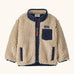Patagonia little kids retro x pile fleece jacket in neutral with a navy trim. Shows a full front zip, side and chest pockets