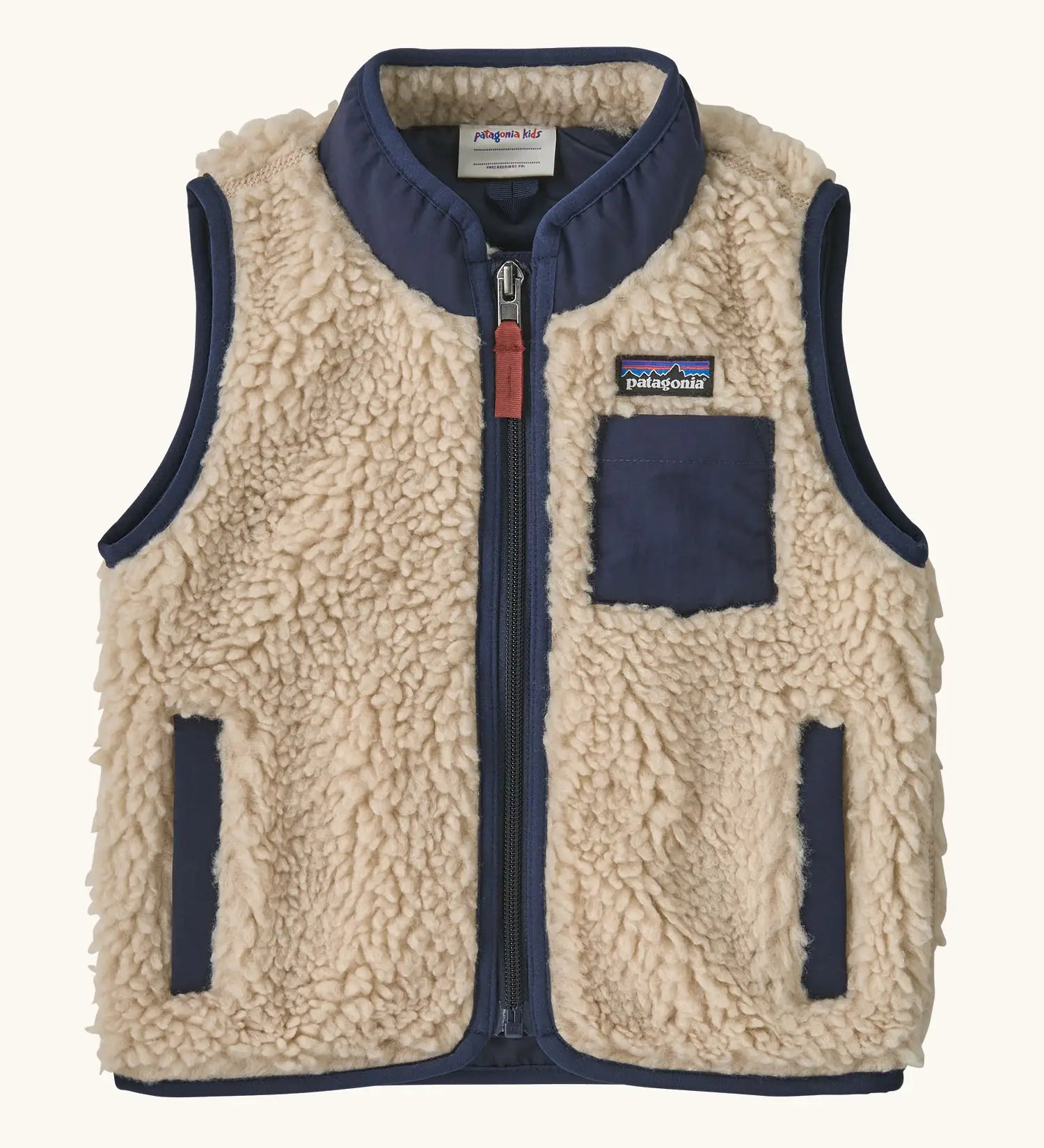 Patagonia 100% recycled polyester little kids retro x high pile fleece vest in beige   with navy trim. Features a full length zip, side and chest pockets 