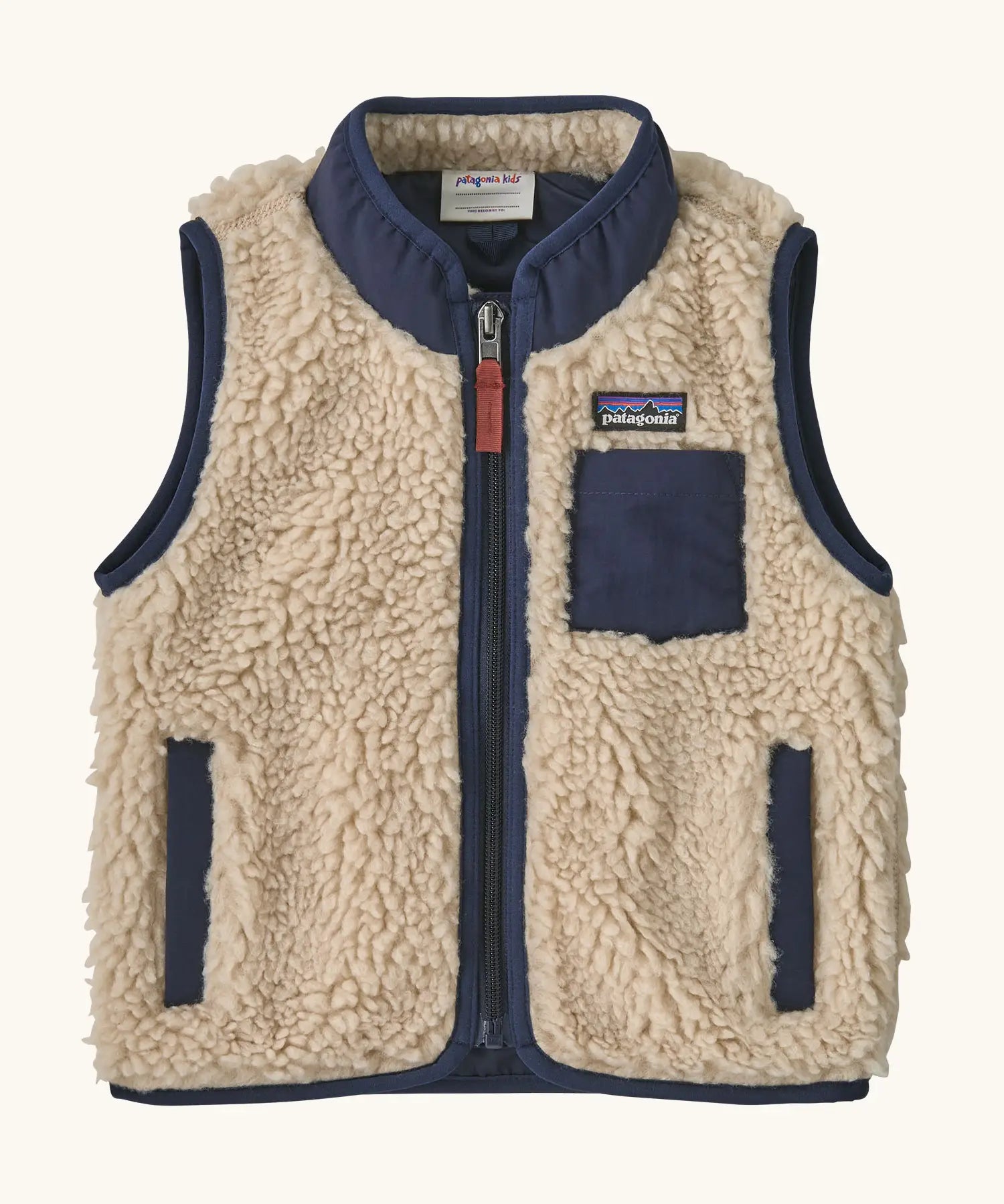 Patagonia 100% recycled polyester little kids retro x high pile fleece vest in beige   with navy trim. Features a full length zip, side and chest pockets 