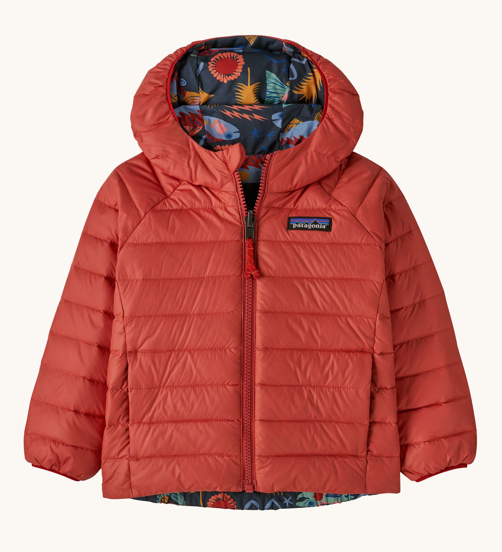 Patagonia little kids down hooded jacket in salmon energy ink black available at Babipur. A red warm reversible jacket with a funky salmon design on the reversible side. Features a a full length zip and 2 side pockets.