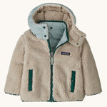 Patagonia little kids tribbles hoody. Showing the natural fleece alternative side. Features a full length zip, a logo patch on the chest and 2 side pockets 
