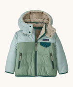 Patagonia little kids tribbles hoody available at Babipur. A reversible coat showing a green and blue hooded coat and natural fleece inner for warmth. Features a small chest pocket with popper fastening and 2 side zip pockets