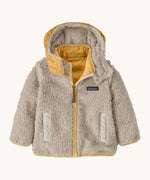Patagonia little kids tribbles hoody. Showing the natural fleece alternative side with light yello trim. Features a full length zip, a logo patch on the chest and 2 side pockets 