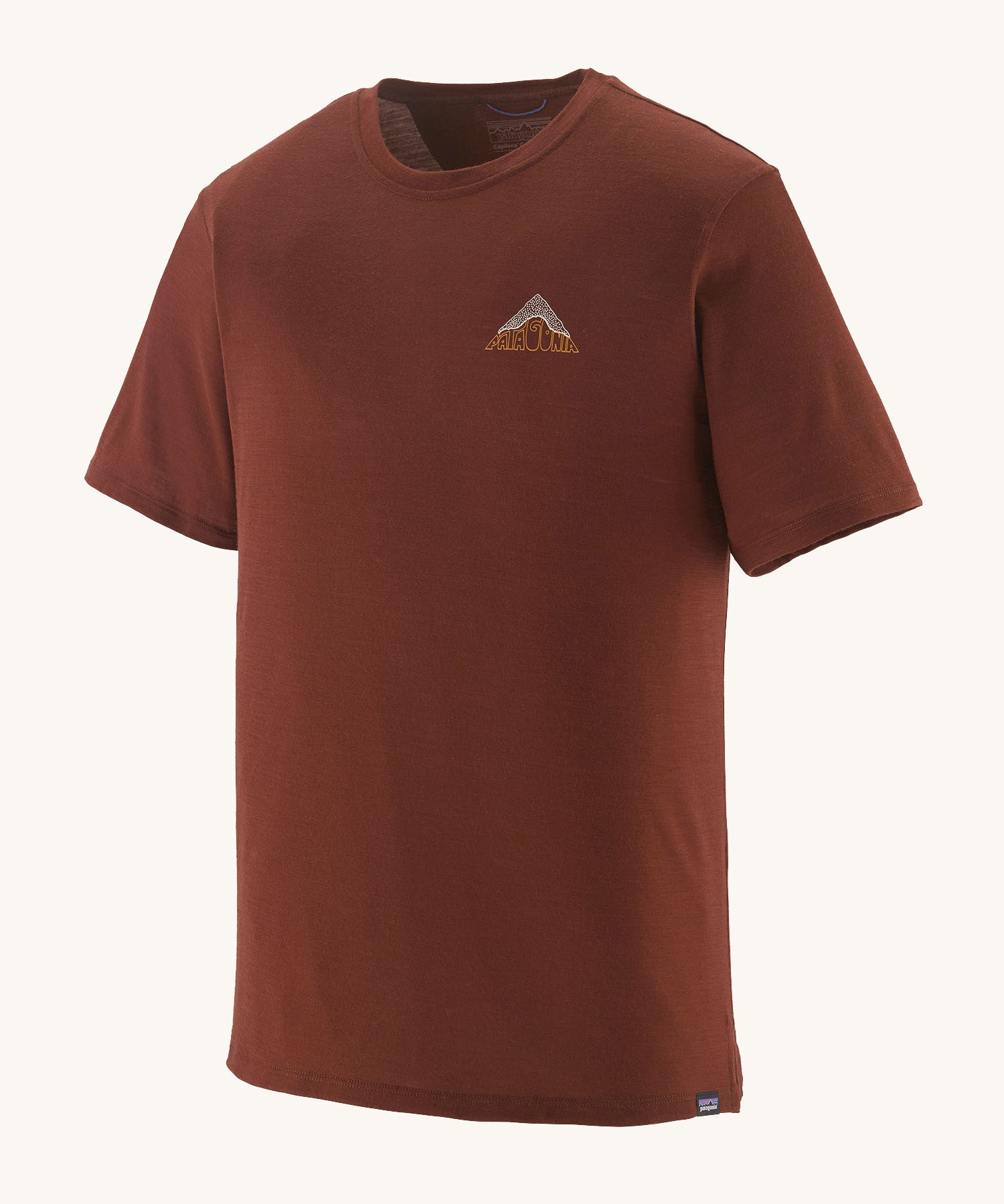 The Patagonia Men's Capilene Cool Merino Graphic Shirt in drift ways dried vanilla available at Babipur. A brown short sleeve top with a mountain graphic on the chest