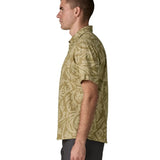 Side of man wearing Patagonia men's buttoned short sleeve shirt in light green with a repeating abstract pattern design 