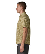 Side of man wearing Patagonia men's buttoned short sleeve shirt in light green with a repeating abstract pattern design 