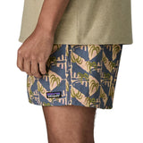 Side of man wearing Patagonia's men's  quick drying baggies shorts with repeating abstract tropical design. Shorts have loose fitting and sit above the knees