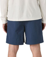Back of Man wearing Patagonia's men's baggies long 7 inch quick drying shorts in dark blue. 