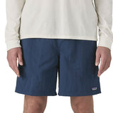 Front of man wearing Patagonia's men's baggies long 7 in shorts in dark blue. Shorts have a relaxed fit and sit above the knees.