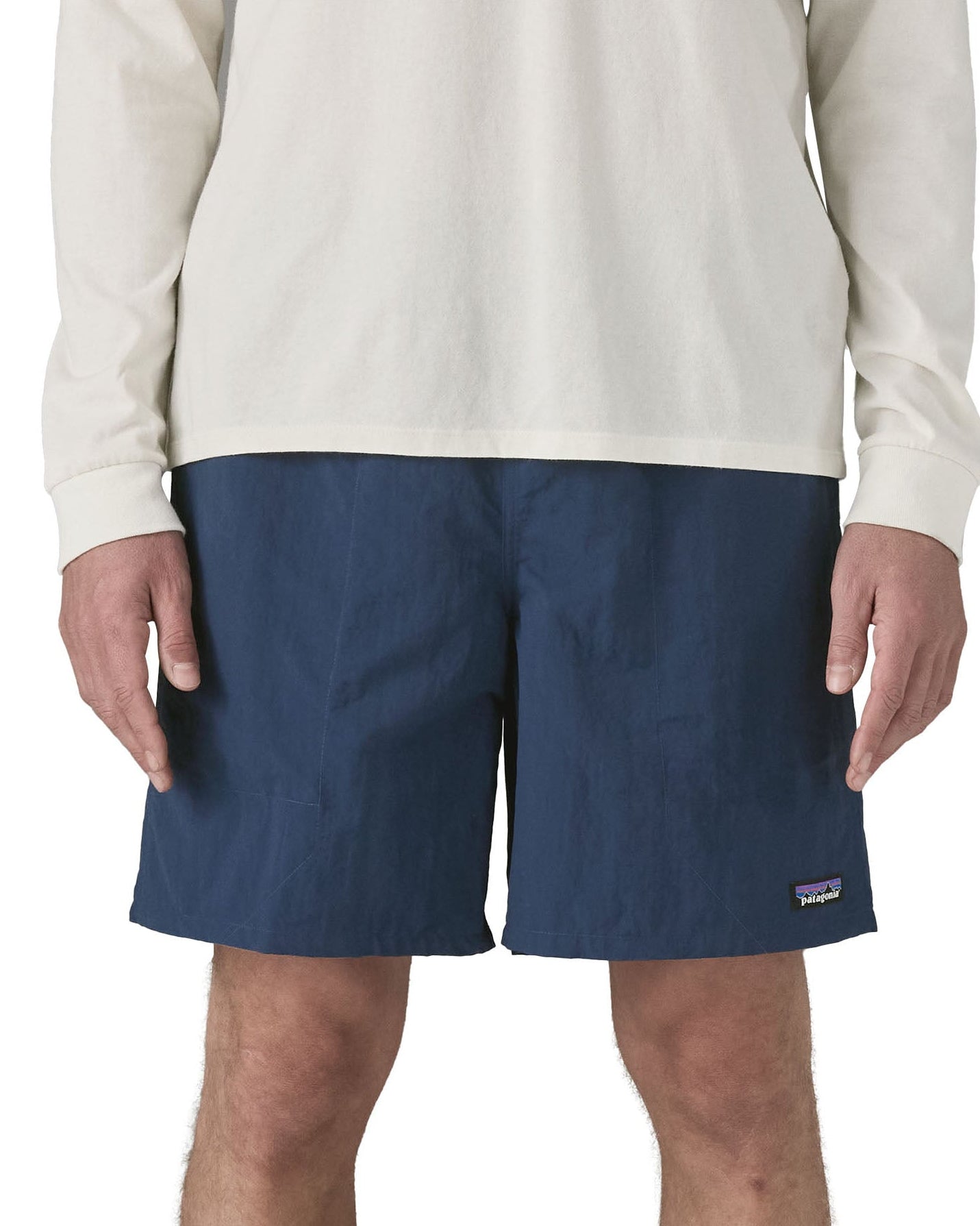 Front of man wearing Patagonia's men's baggies long 7 in shorts in dark blue. Shorts have a relaxed fit and sit above the knees.