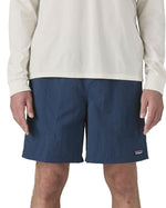 Front of man wearing Patagonia's men's baggies long 7 in shorts in dark blue. Shorts have a relaxed fit and sit above the knees.