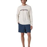 Man wearing Patagonia's men's baggies long quick drying shorts in dark blue. Shorts have a relaxed fit and sit above the knees