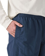 Man wearing Patagonia's men's baggies long 7 in shorts in dark blue with hand in side pocket