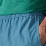 Close up of man wearing Patagonia's men's quick drying baggies shorts in light blue. Shows elasticated waist band
