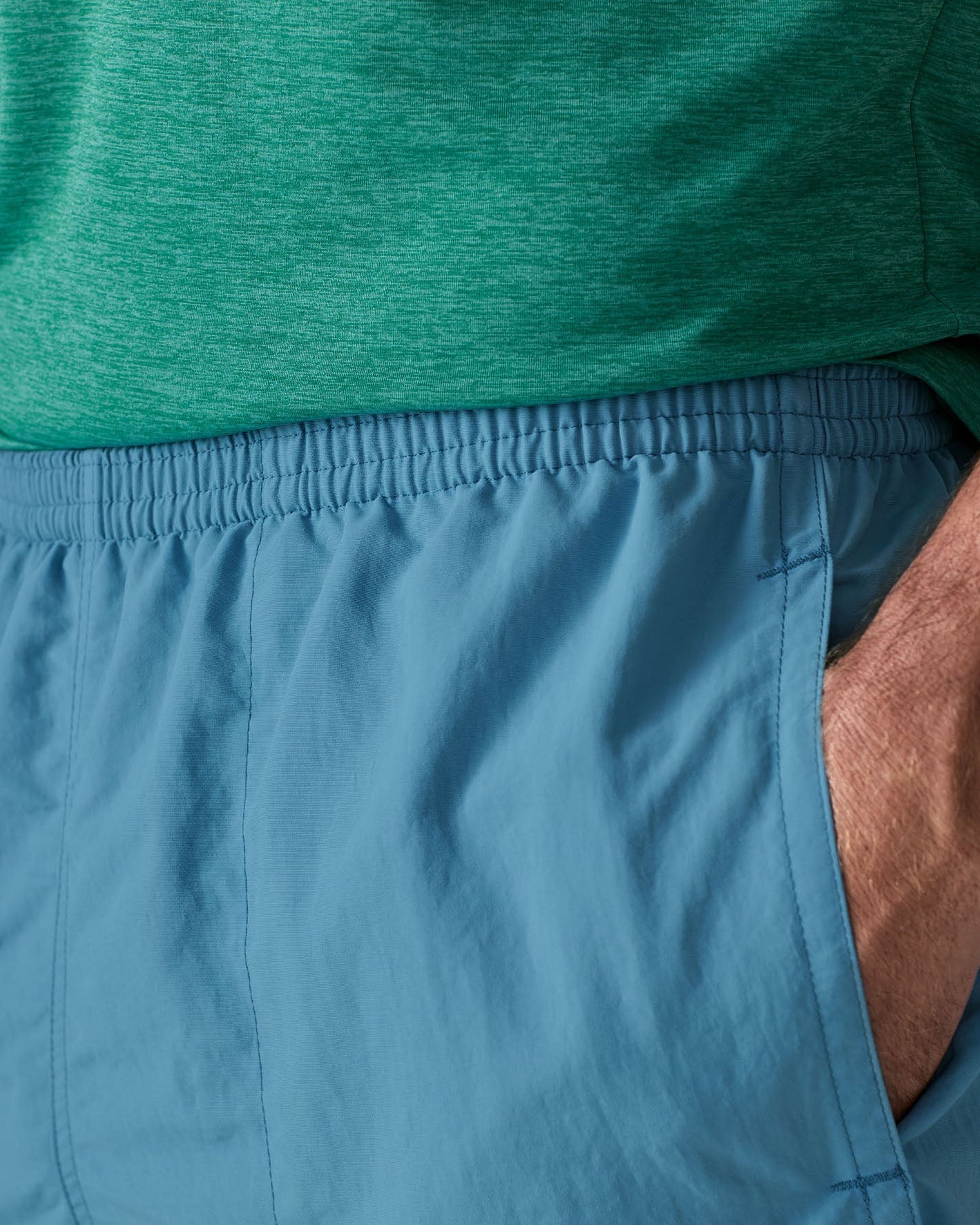 Close up of man wearing Patagonia's men's quick drying baggies shorts in light blue. Shows elasticated waist band