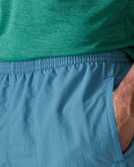 Close up of man wearing Patagonia's men's quick drying baggies shorts in light blue. Shows elasticated waist band