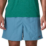 Man wearing Patagonia's men's  quick drying men's baggies shorts in light blue. Shorts have loose fitting and sit above the knees