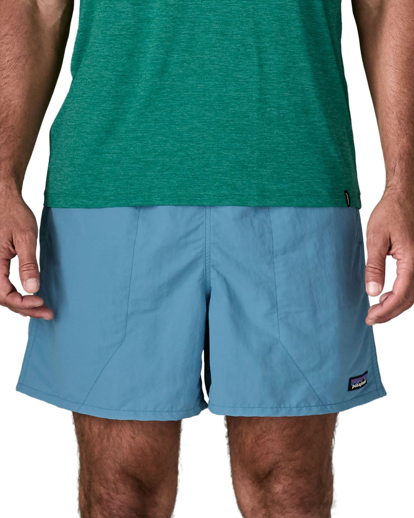 Man wearing Patagonia's men's  quick drying men's baggies shorts in light blue. Shorts have loose fitting and sit above the knees