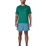 Man wearing Patagonia's men's  quick drying baggies shorts in light blue. Shorts have loose fitting 