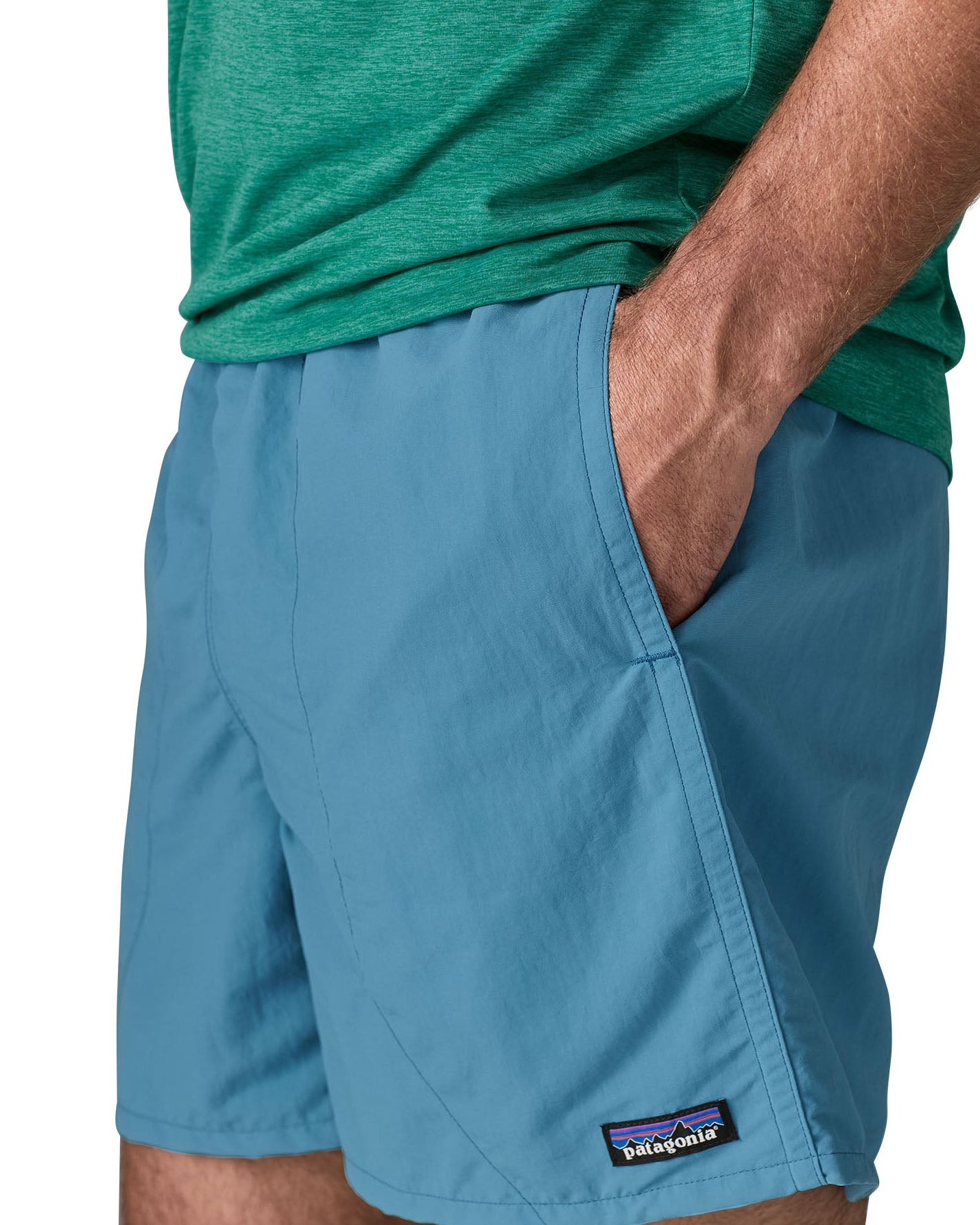 Man wearing Patagonias men's quick drying baggies shorts in light blue with hand in side pocket