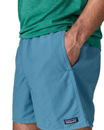 Man wearing Patagonias men's quick drying baggies shorts in light blue with hand in side pocket