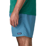 Side of man wearing Patagonia's men's  quick drying baggies shorts in light blue. Shorts have loose fitting and sit above the knees