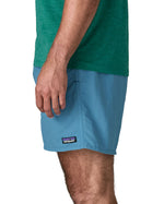 Side of man wearing Patagonia's men's  quick drying baggies shorts in light blue. Shorts have loose fitting and sit above the knees