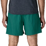 Back of man wearing Patagonia's men's  quick drying baggies shorts in teal green. Shorts have loose fitting and sit above the knees