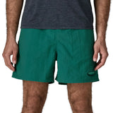 Man wearing Patagonia's men's  quick drying men's baggies shorts in teal green. Shorts have loose fitting and sit above the knees