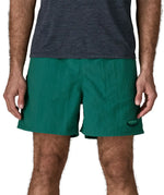 Man wearing Patagonia's men's  quick drying men's baggies shorts in teal green. Shorts have loose fitting and sit above the knees
