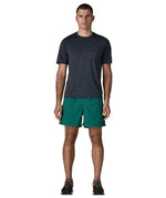 Man wearing Patagonia's men's  quick drying baggies shorts in teal green. Shorts have loose fitting 