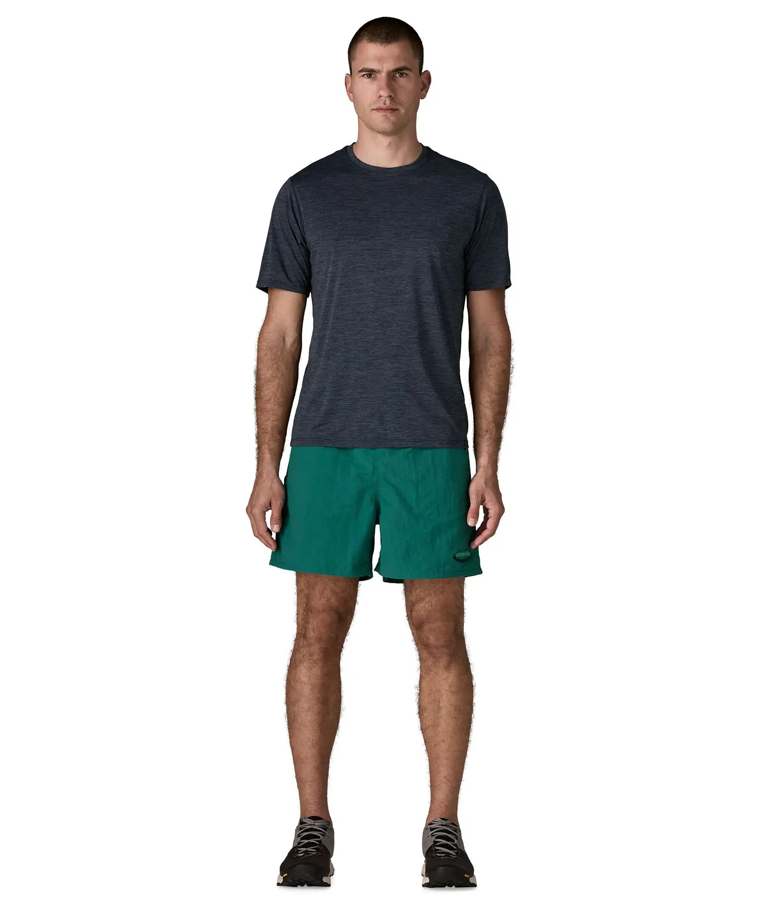Man wearing Patagonia's men's  quick drying baggies shorts in teal green. Shorts have loose fitting 