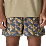 Man wearing Patagonia's men's  quick drying men's baggies shorts with repeating tropical design. Shorts have loose fitting and sit above the knees