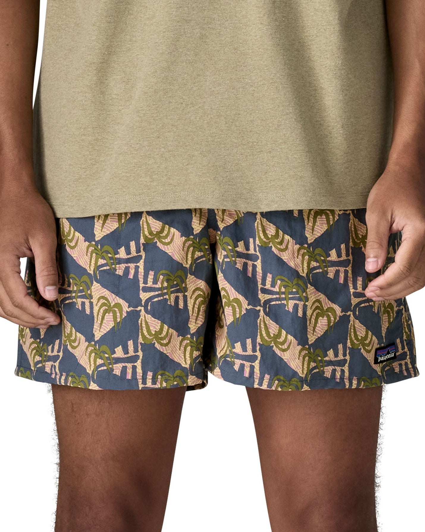 Man wearing Patagonia's men's  quick drying men's baggies shorts with repeating tropical design. Shorts have loose fitting and sit above the knees