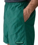 Man wearing Patagonias men's quick drying baggies shorts in teal green with hand in side pocket