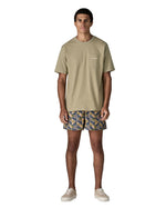 Man wearing Patagonia's quick drying baggies shorts with repeating abstract tropical design. Shorts have loose fitting 