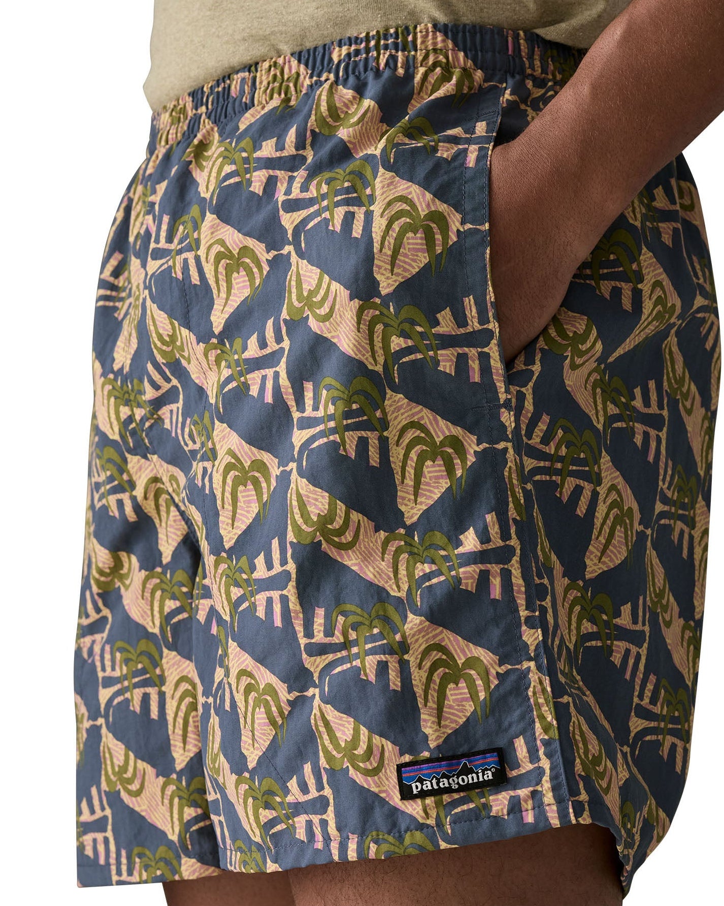 Man wearing Patagonia's men's quick drying baggies shorts with repeating abstract tropical design with hand in side pocket