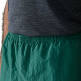 Close up of man wearing Patagonia's men's quick drying baggies shorts in teal green. Shows elasticated waist band
