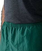 Close up of man wearing Patagonia's men's quick drying baggies shorts in teal green. Shows elasticated waist band