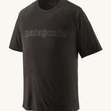 The Patagonia Men's Cap Cool Trail Graphic T-Shirt - Black. An organic cotton, adult t-shirt in black, with lack textured Patagonia text on the front of the top. On a plain background