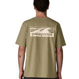 Man wearing Patagonia's men boardshort responsibili tee in light green. Shows a cream wave brand logo on the upper back