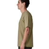 Side of man wearing Patagonia's men boardshort logo pocket responsibili tee in light green. T-shirt has a classic crewneck design