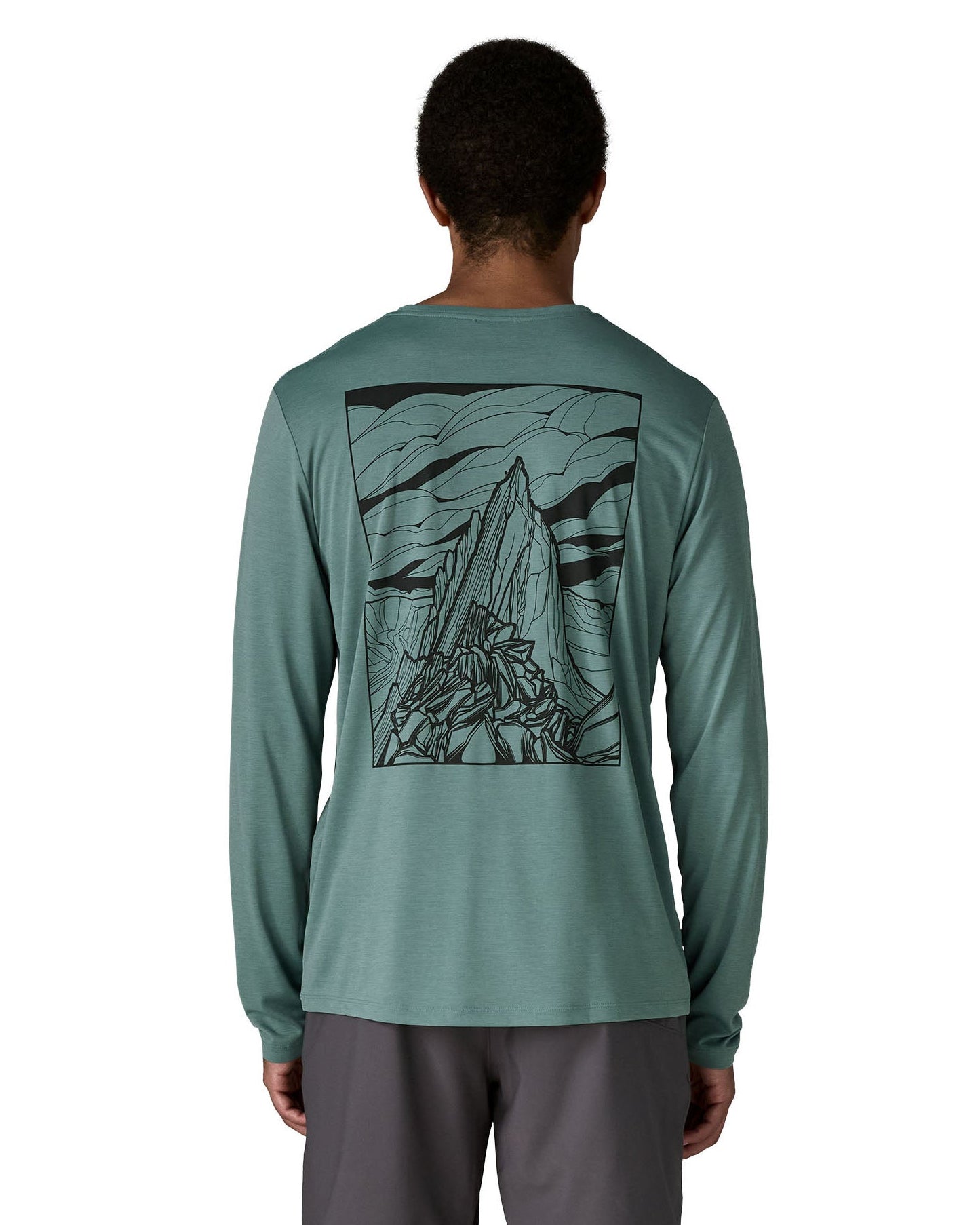 Man wearing Patagonia men's capilene cool daily long sleeve t-shirt in sage blue with black mountain graphic on upper back